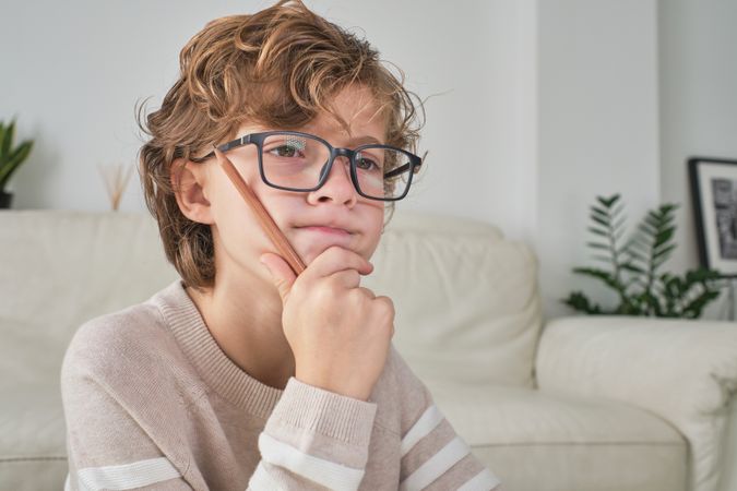 Puzzled boy in glasses looking at screen
