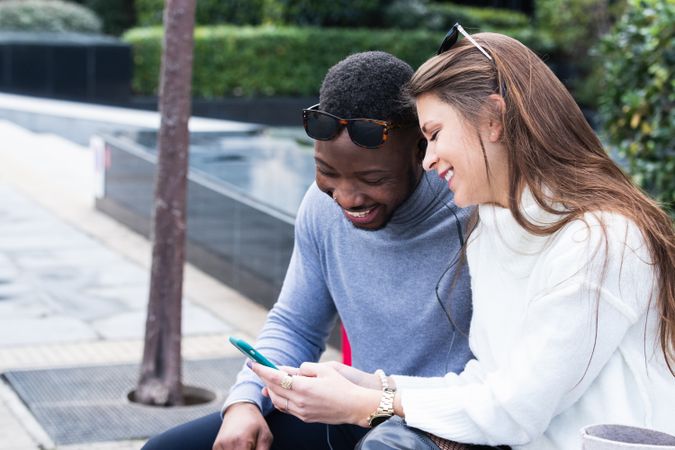 Joyful multiethnic couple using smartphone in park