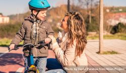 Mother smiling up at little boy on bike 48mOvb