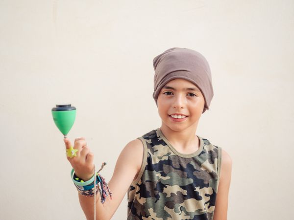 Smiling boy spinning tops on finger and looking at camera