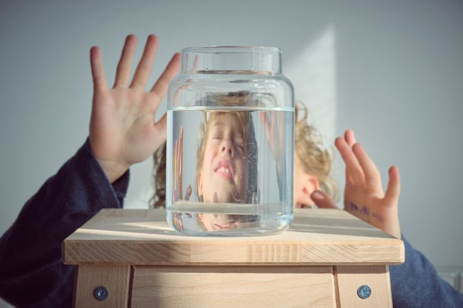 Terrified boy reflection in glass jar with water