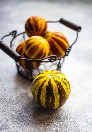 Organic mini melons in wire fruit basket on counter