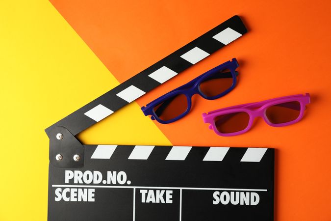 3d glasses and clapperboard on two tone background, space for text