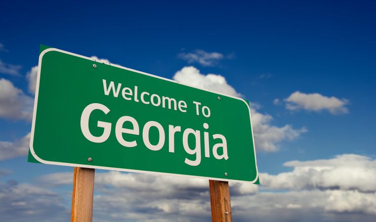 Welcome To Georgia Green Road Sign Over Blue Sky with Some Clouds.