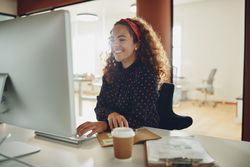 Smiling woman working at a computer with coffee