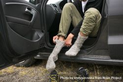 Man sitting on car putting on thermal socks 5oPnx4