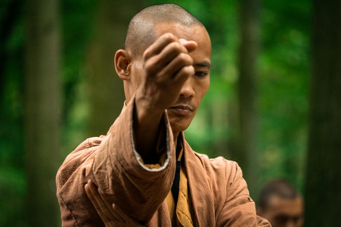 Asian man practicing martial arts in forest