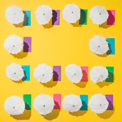 Pattern of sun umbrellas and multicolored towels in rows on yellow