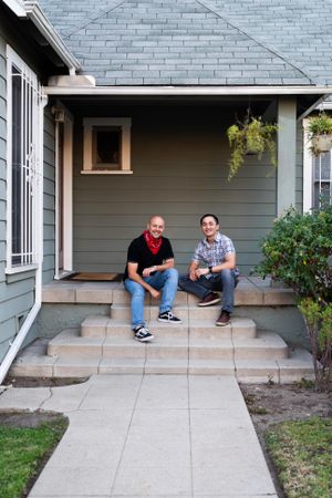 Portrait of two men sit on a porch smiling at the camera