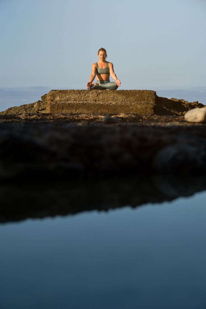 Woman sitting on stone and practicing yoga