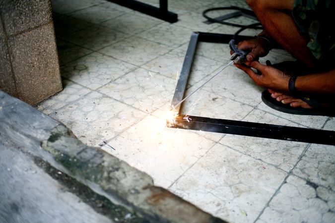 Person welding a metal frame on the ground