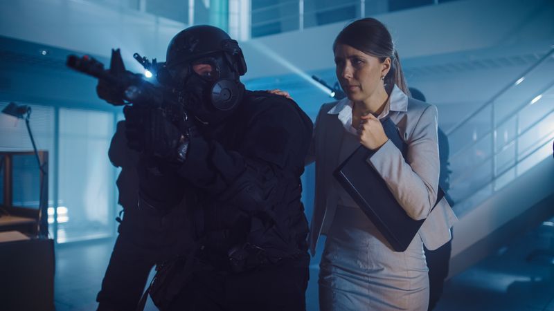 Masked Squad of Armed SWAT Police Officers Rescue a Female Hostage in a Dark Seized Office Building with Desks and Computers.