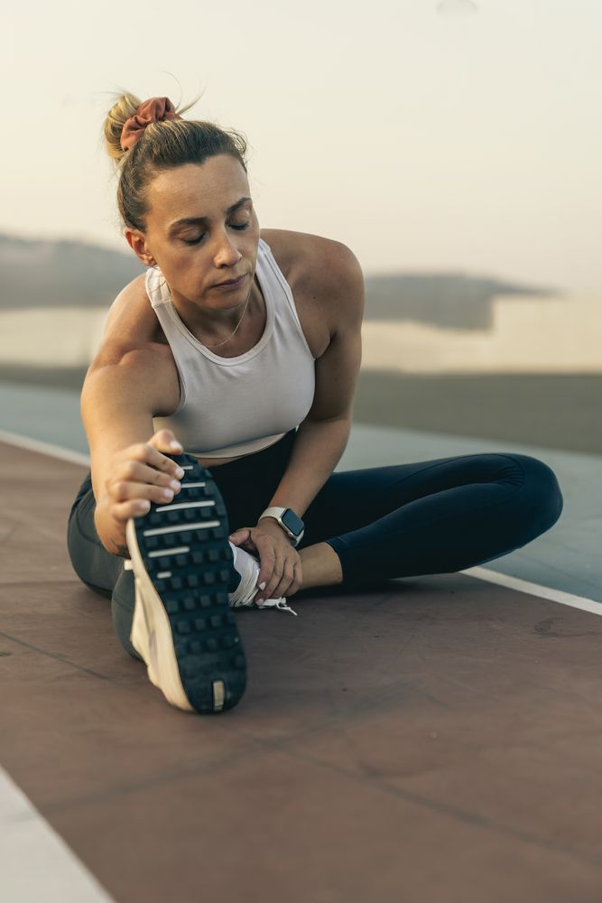 Fit woman doing a hamstring stretch on a running track after her workout