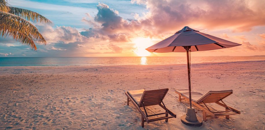 Tropical beach at sunset with lounge chairs