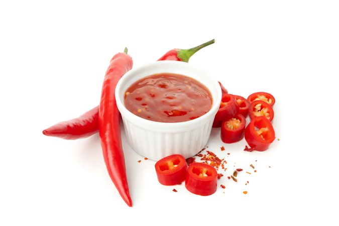 Chilli pepper and bowl of sauce isolated on plain background