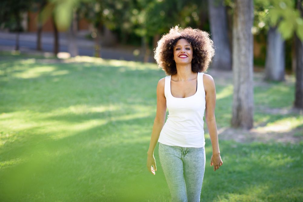 Young Black woman with afro hairstyle walking through park