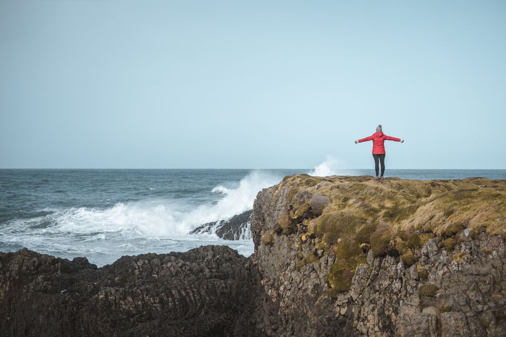 Woman on top of rock with sea surf
