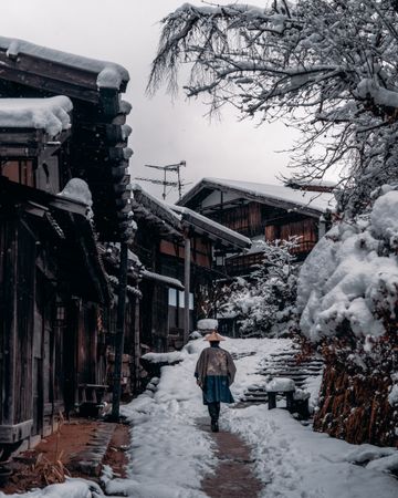 Back view of Japanese person walking in snow-covered alley in Japan