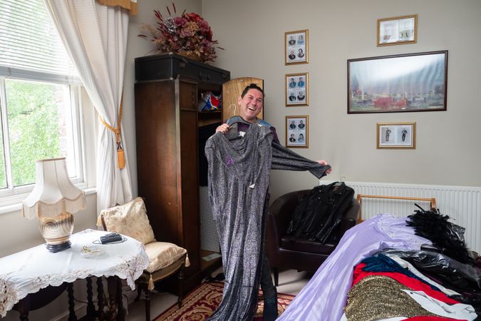 Man smiling at home with dress collection