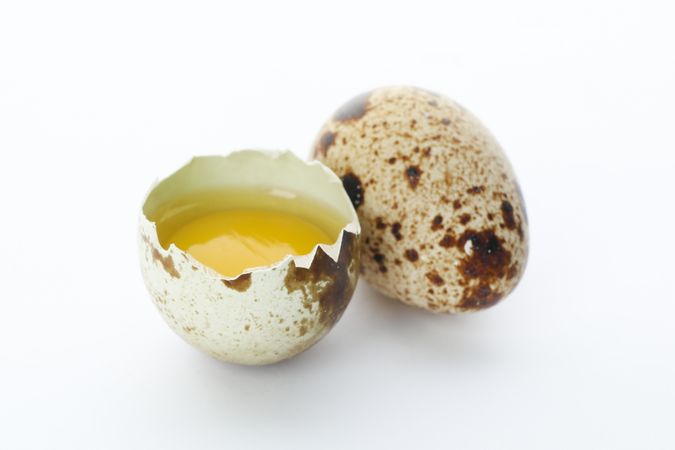 Quail egg and half yolk isolated on light background