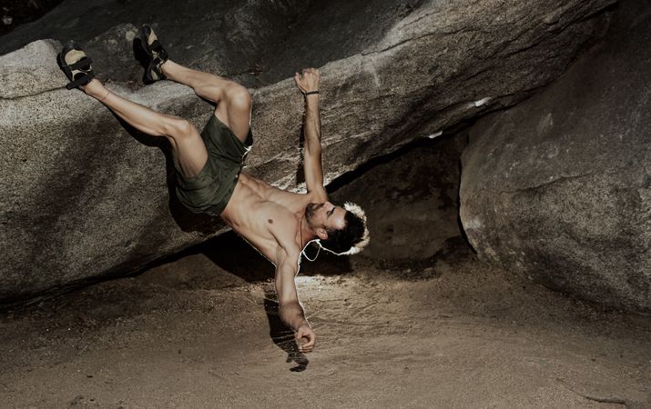 Man practicing rock climbing among large rocks in a forest