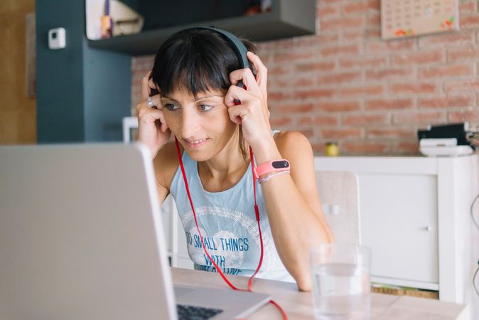 Woman adjusting headphones while working at laptop