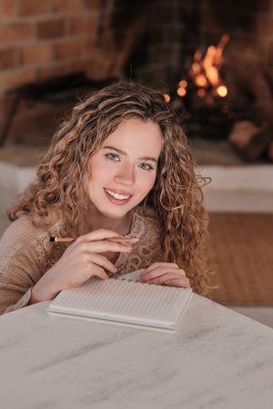 Smiling woman taking notes and looking at camera