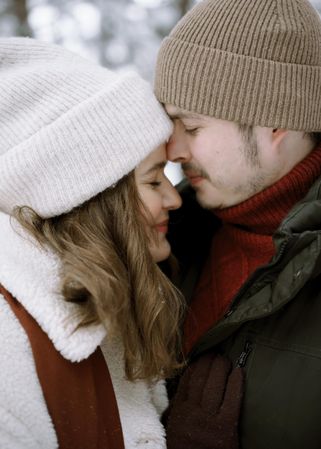 Man and woman in knit cap hugging each other