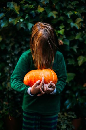 Child with pumpkin pretending monster in Halloween style