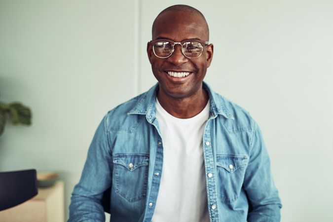 Man smiling in jean jacket and glasses