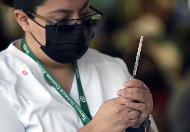 Nurse with facemask holding a syringe