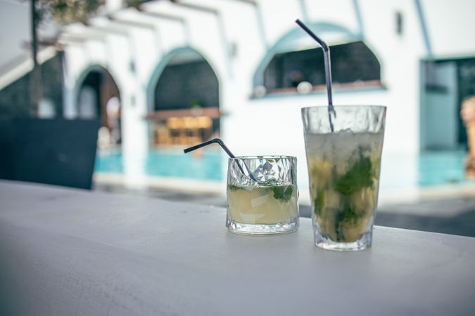 Two cocktails on a table poolside