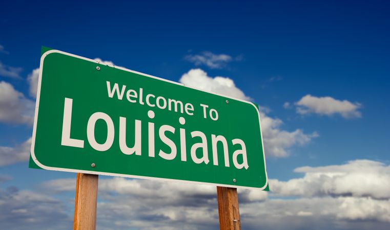 Welcome To Louisiana Green Road Sign Over Blue Sky with Some Clouds.
