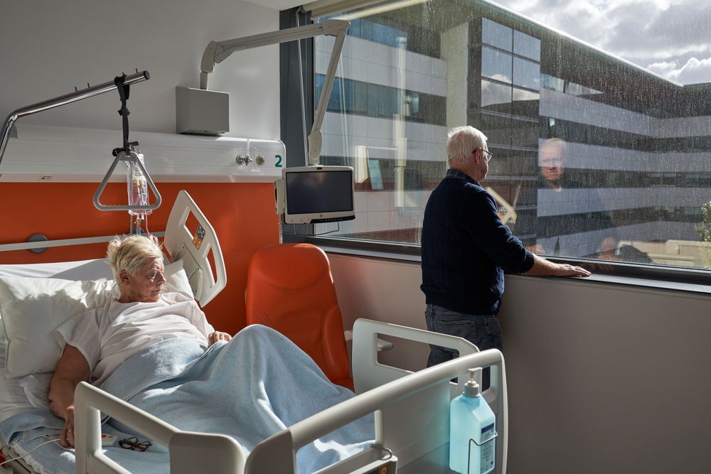 Thoughtful mature man standing near window during visit of unwe