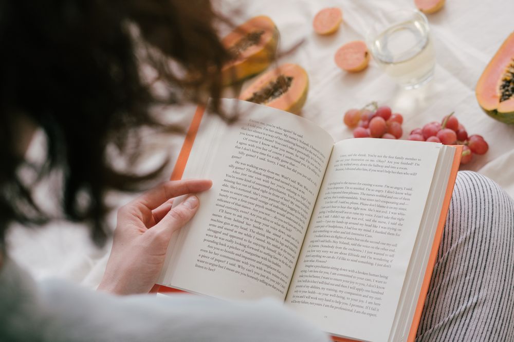 Back view of woman reading a book near fruits