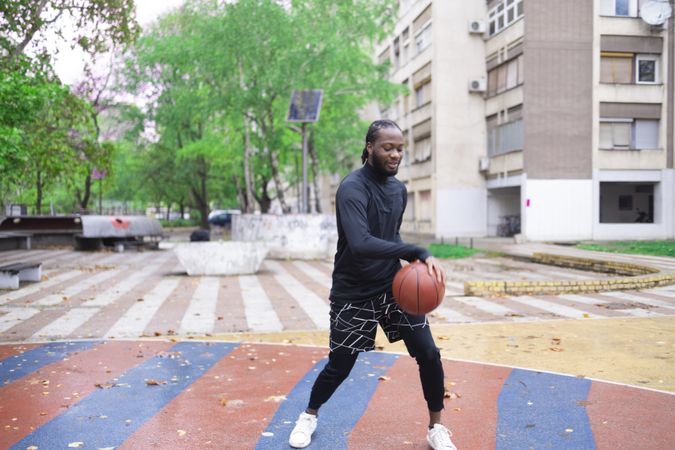 Young Man Dribbling Basketball Outdoors in Springtime.