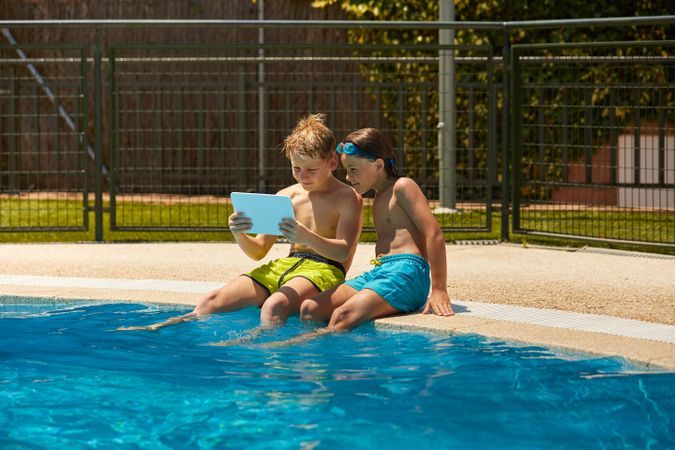 Boys on poolside browsing tablet