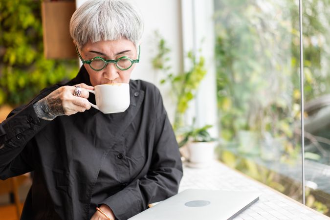 Mature Asian woman sipping coffee in cafe