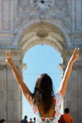 Happy woman showing peace signs while standing against picturesque arch