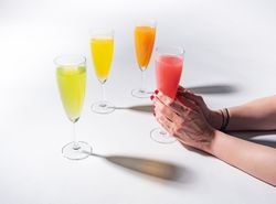 Hand and glasses of bright colorful drinks on table