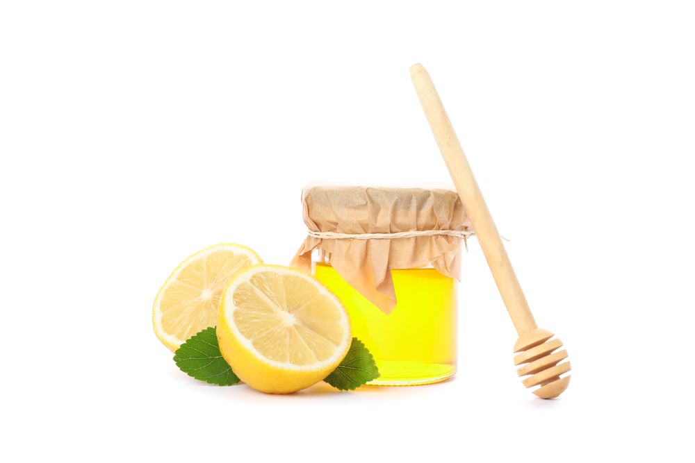 Dipper, lemons and glass jar with honey isolated on studio background