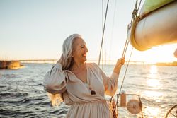 Stylish mature woman standing on a boat at sunset
