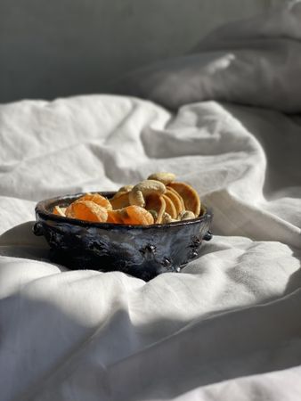 Breakfast in a bowl served in morning light on a duvet