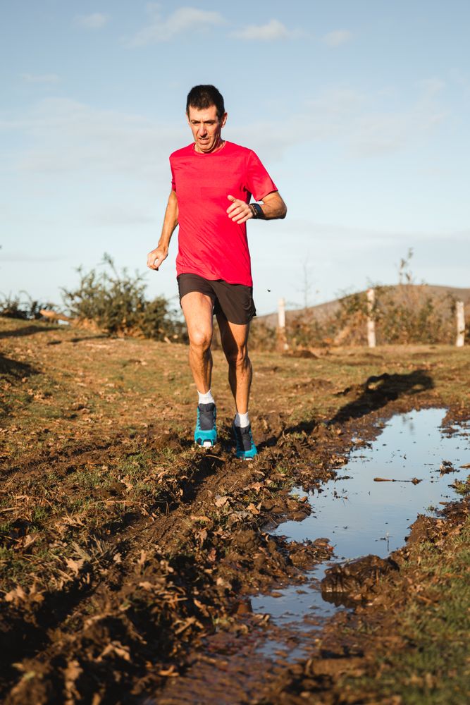Sportsman running on dirty road in countryside