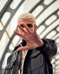 Young man with his hand to the camera blocking his face