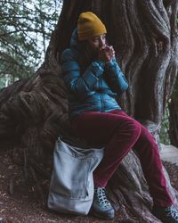 Woman sitting on tree root and warming hands