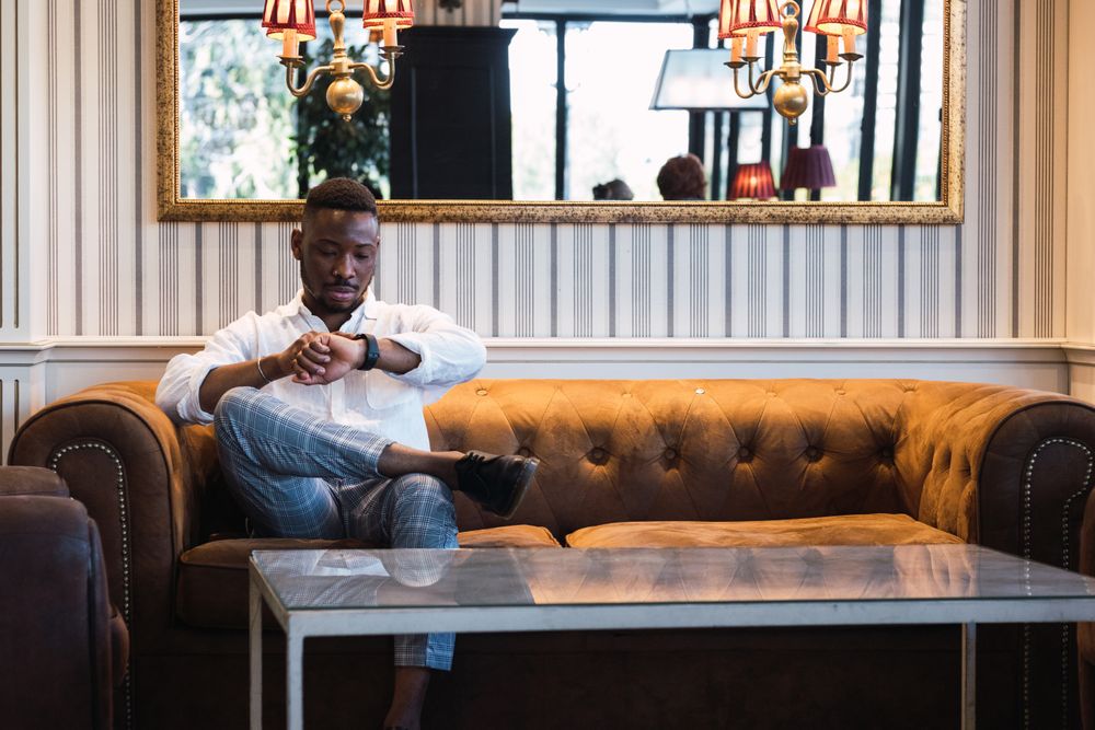 Stylish Black man checking time on wristwatch