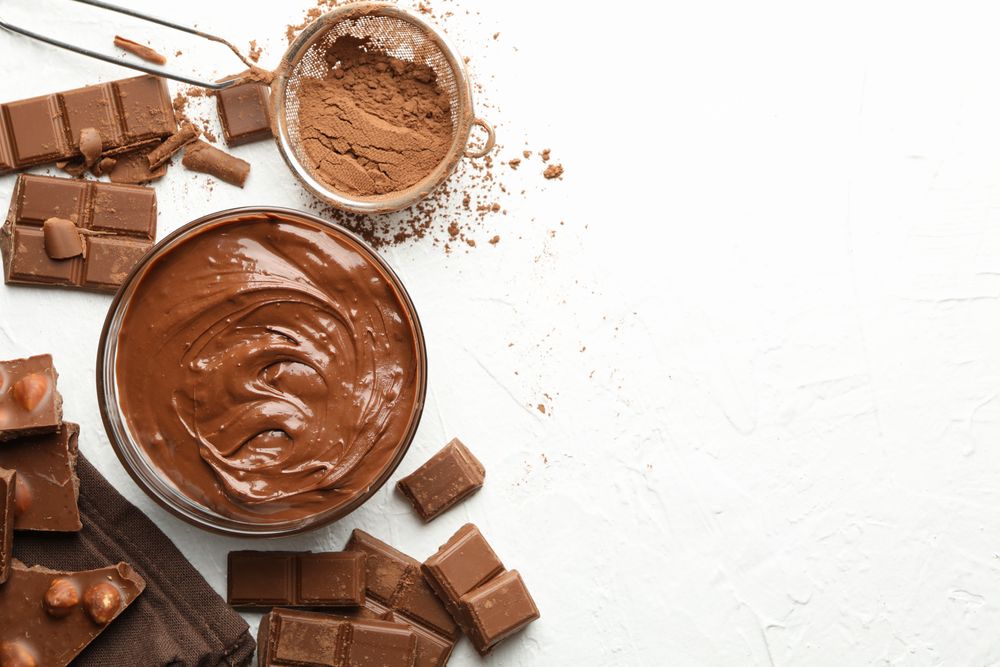 Chocolate, melted chocolate and powder on light background