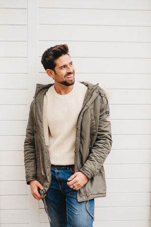 Cheerful stylish male standing against wooden wall