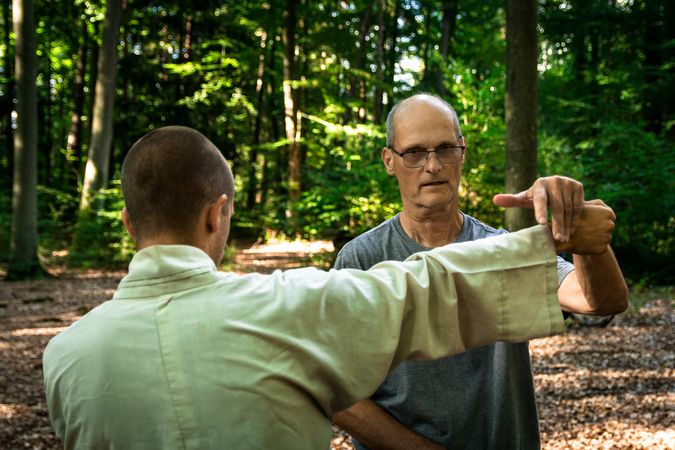 man training martial arts student in forest